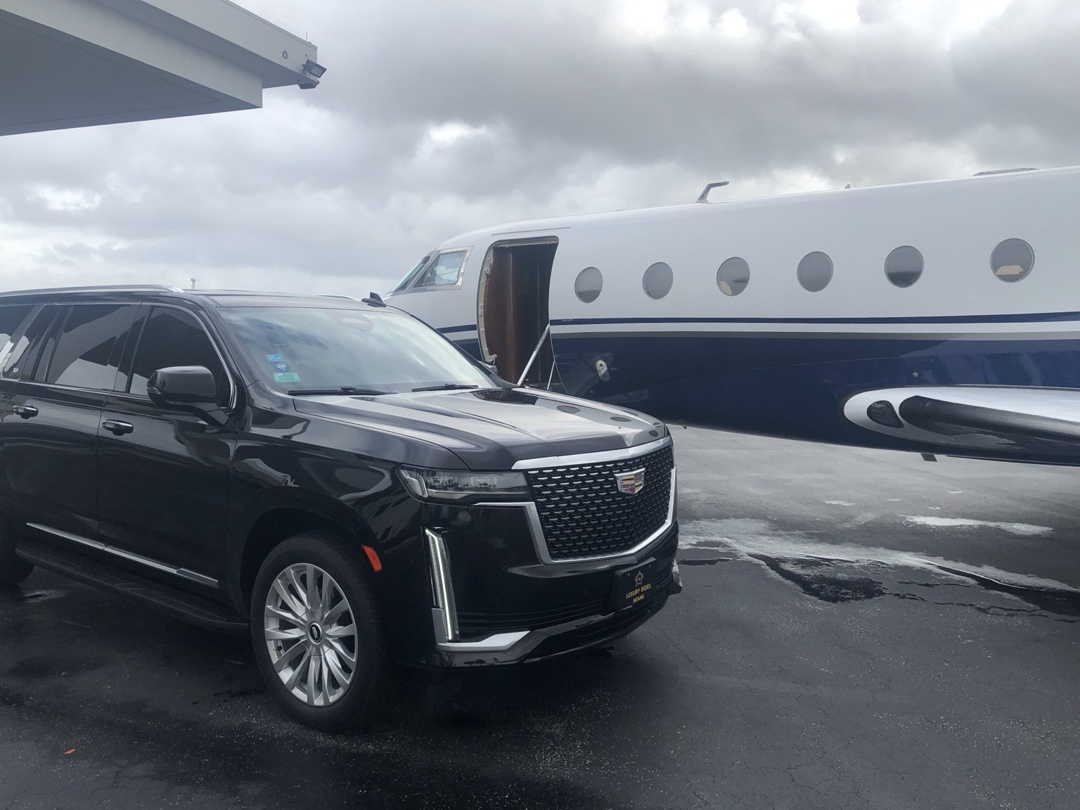 Luxury Rides Miami black Cadillac Escalade beside a private jet